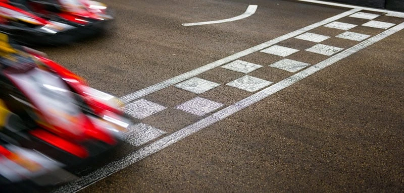 Racerkart passerar mållinjen i hög hastighet på en bana.